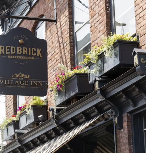 A brick building with a sign hanging off of it for the Redbrick Inn