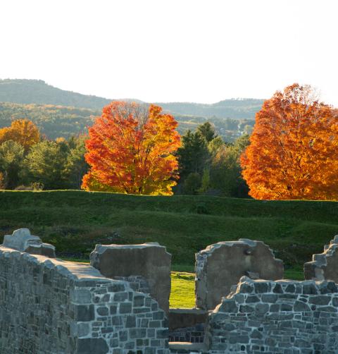 Fort ruins in front of bright orange trees in the fall