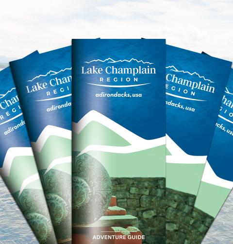 A variety of Lake Champlain Region visitor guides with a water background.