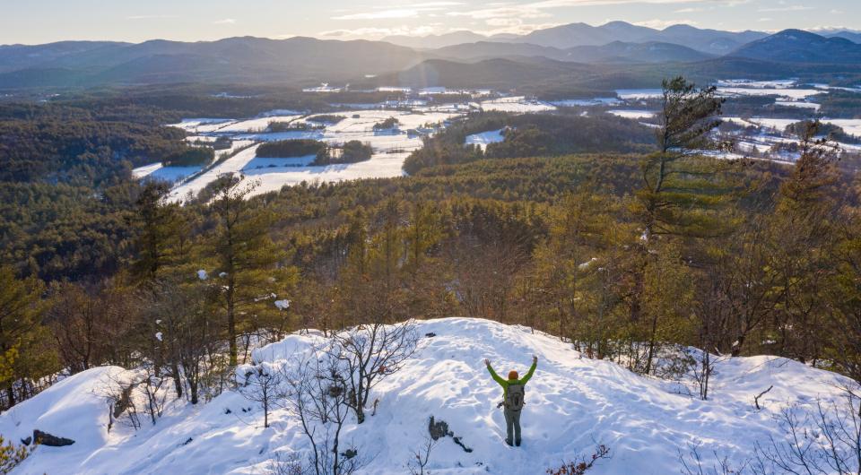 A person on the summit of Coon Mountain in the winter.