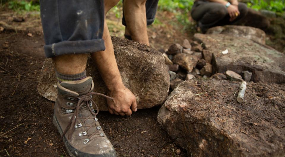 A person lifting a large rock