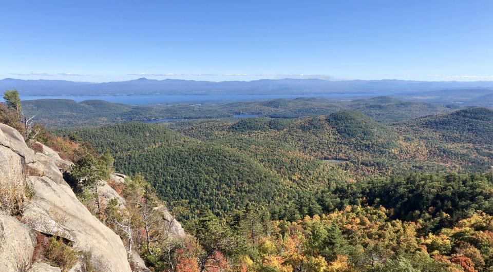 A rocky cliff looks over a colorful fall view