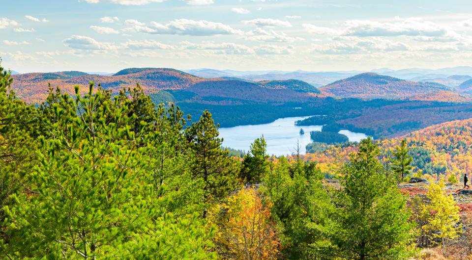 A large pond nestled among colorful fall mountains. 