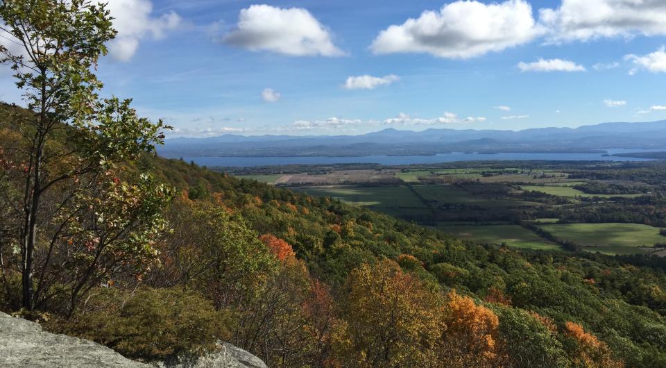 A fall view from a short peak of surrounding woods and a lake