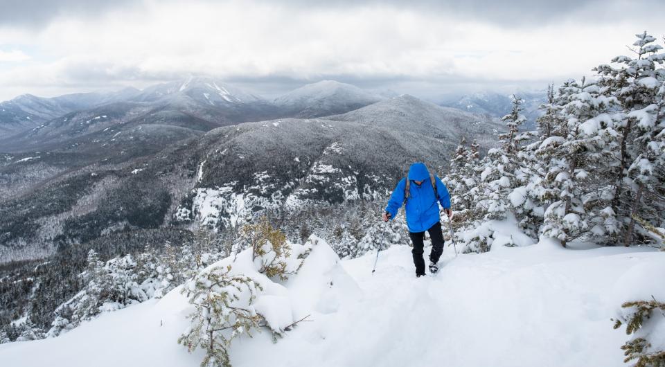 A man walks up a snowy mountain trail