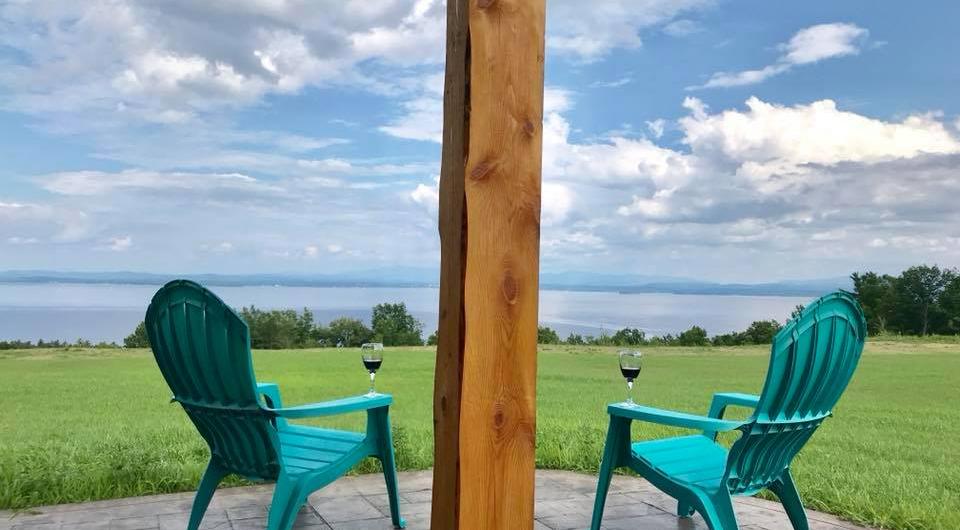 Two Adk chairs with wineglasses on arm overlooking Lake Champlain 