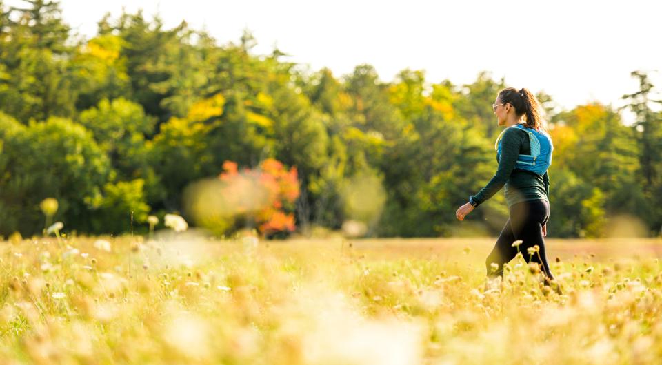 A woman walks through a field of golden grasses