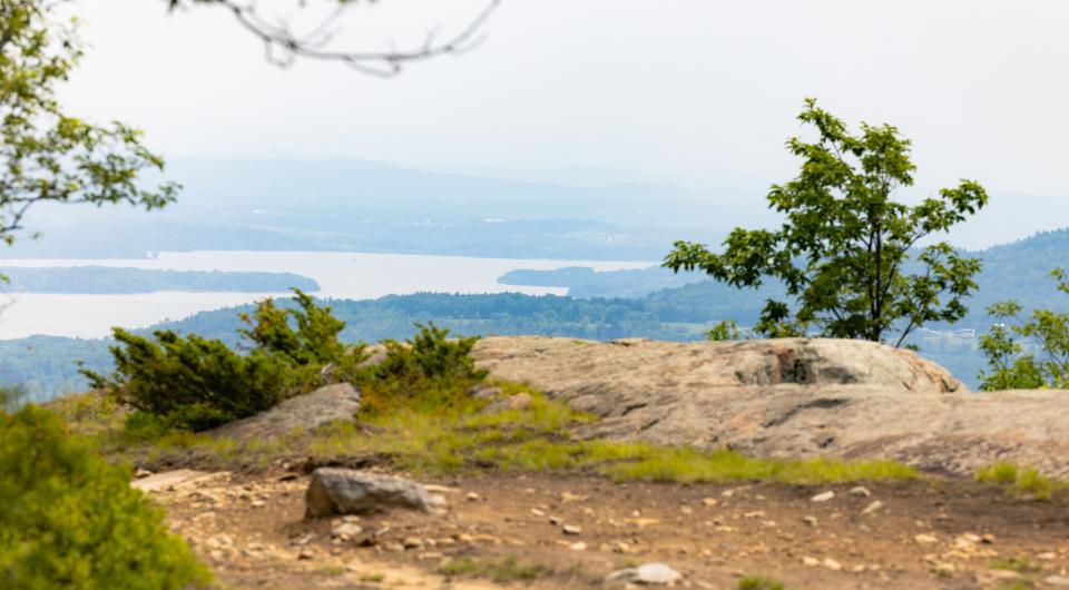 An open summit looking out towards narrow Lake Champlain.