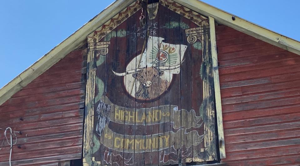 A barn with a Highland cow sign above the doors.