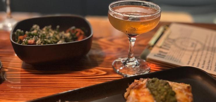 A close-up of a restaurant table with small fine dining plates and a cocktail.