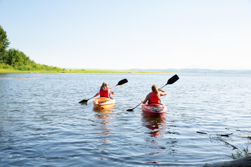 Two women paddle out onto a lake in kayaks.