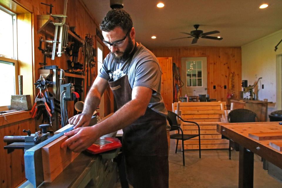 Eain works on a cutting board in the back room of his workshop.