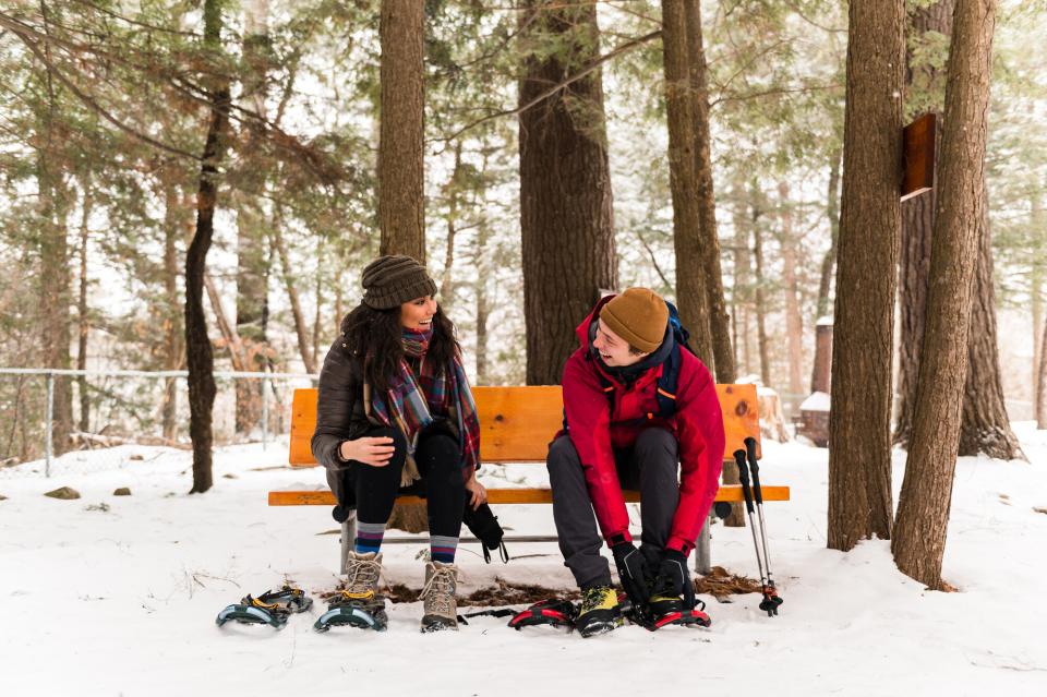 two people strapping on their snowshoes