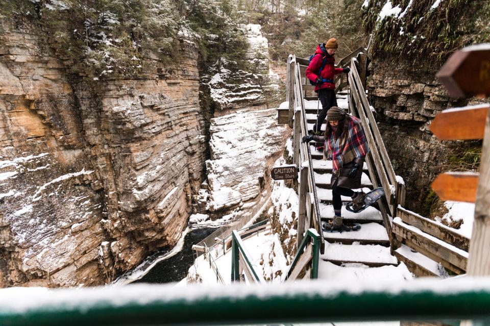 A man and woman make their way down the stairs that line the side of the chasm. You can see the length of the chasm behind them.