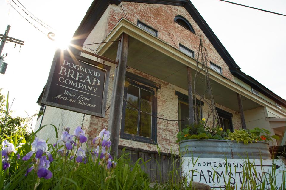 The rough brick exterior of a two-story house with a sign that reads "Dogwood Bread Company."