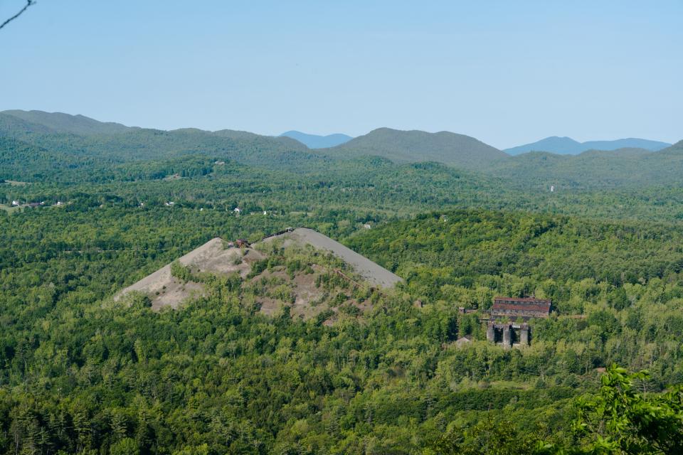 A massive pile of mining tailings in the middle of a green forest