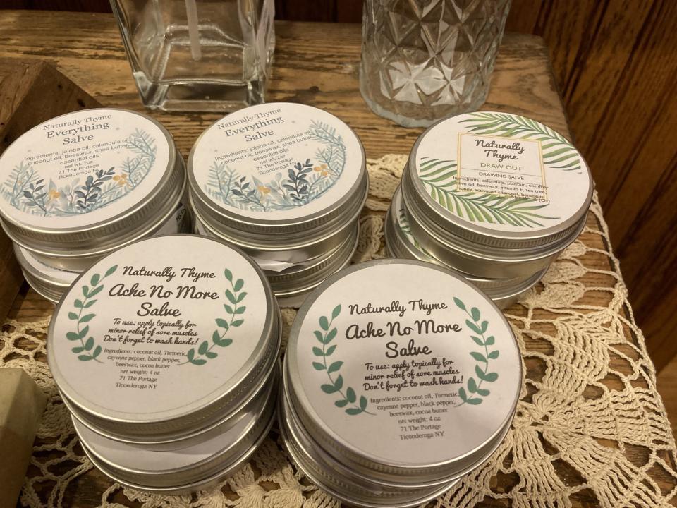 A wooden table with multiple stacks of metal tins with salves