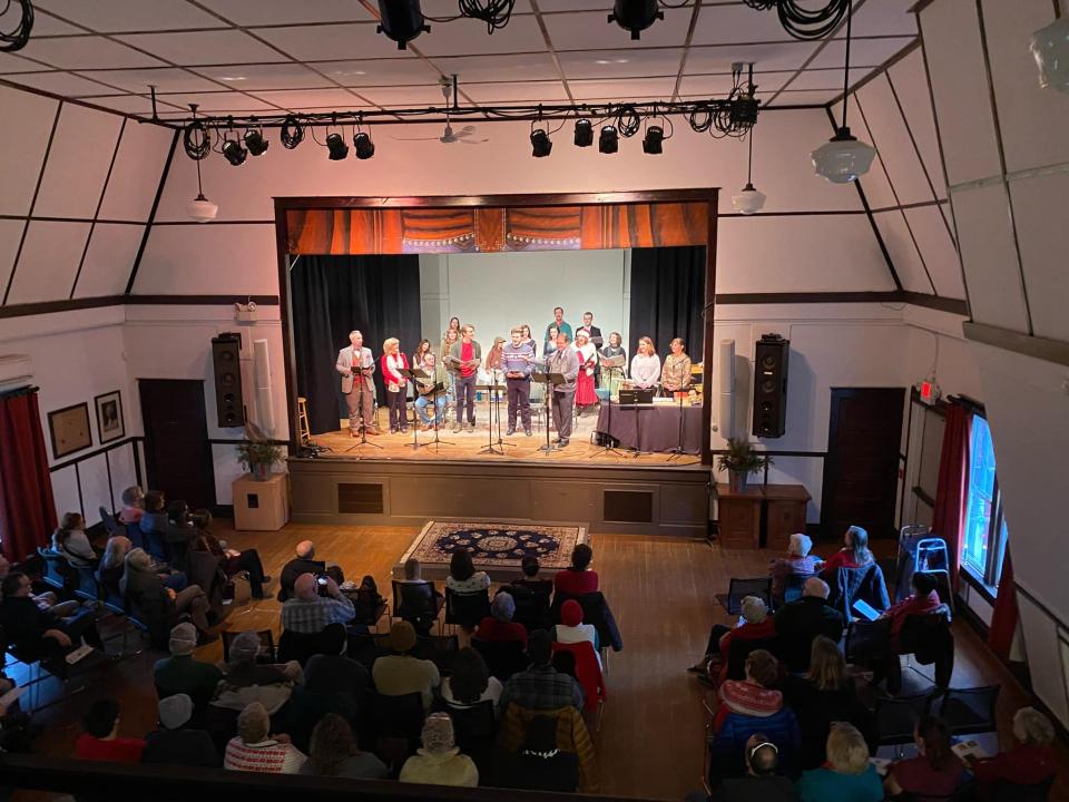 A group of people perform on a stage to a group of onlookers