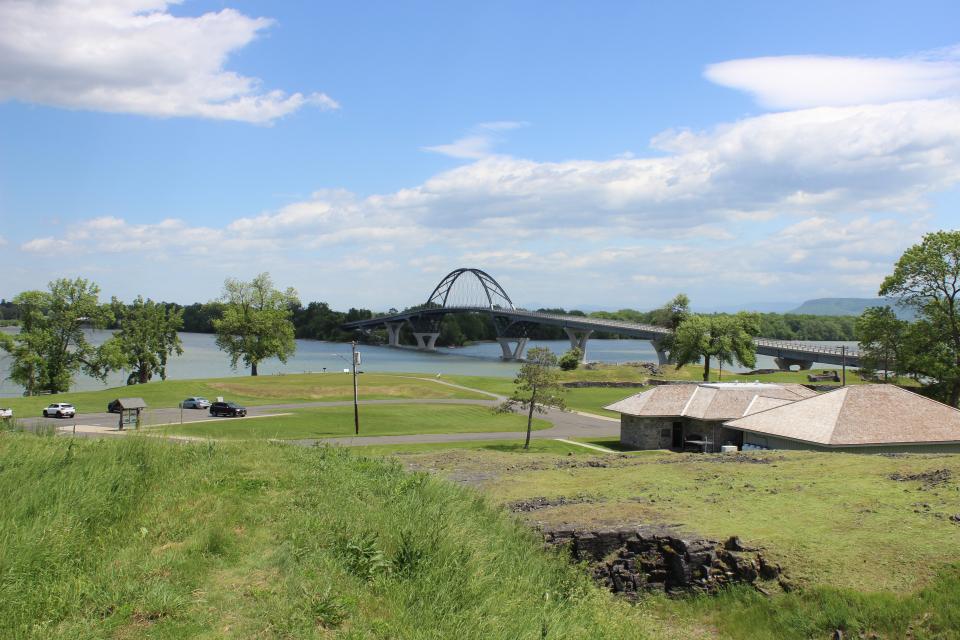 A park next to a lake with a bridge going over it.