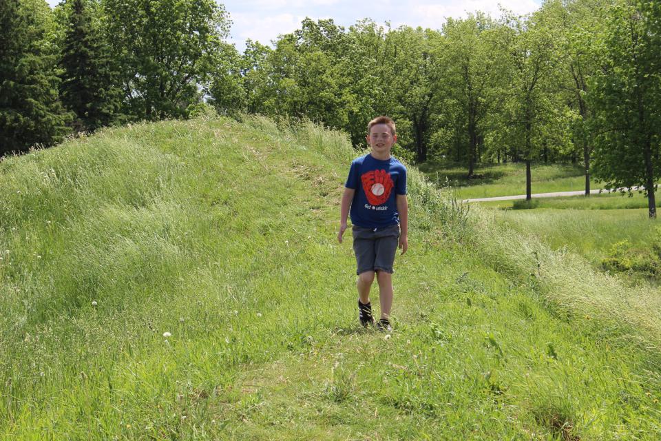 A young boy walks down a grassy hill.