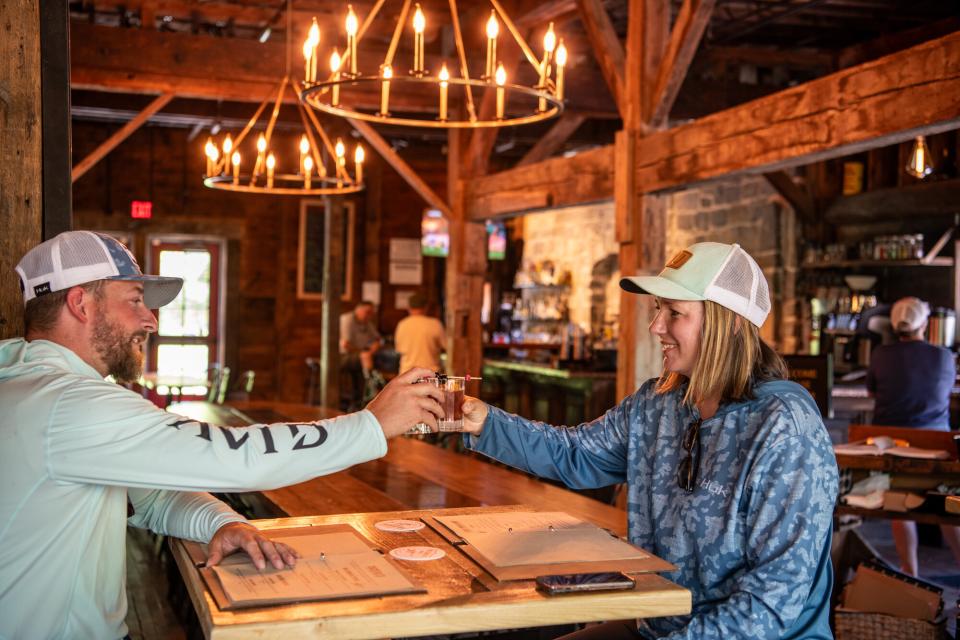 A man and woman cheers in a rustic restaurant.