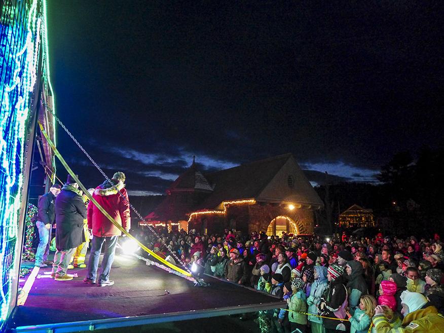 People on a train car stage talk to a crowd at night.