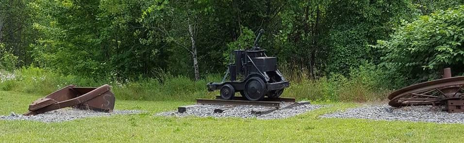 An old mine cart on display outdoors.